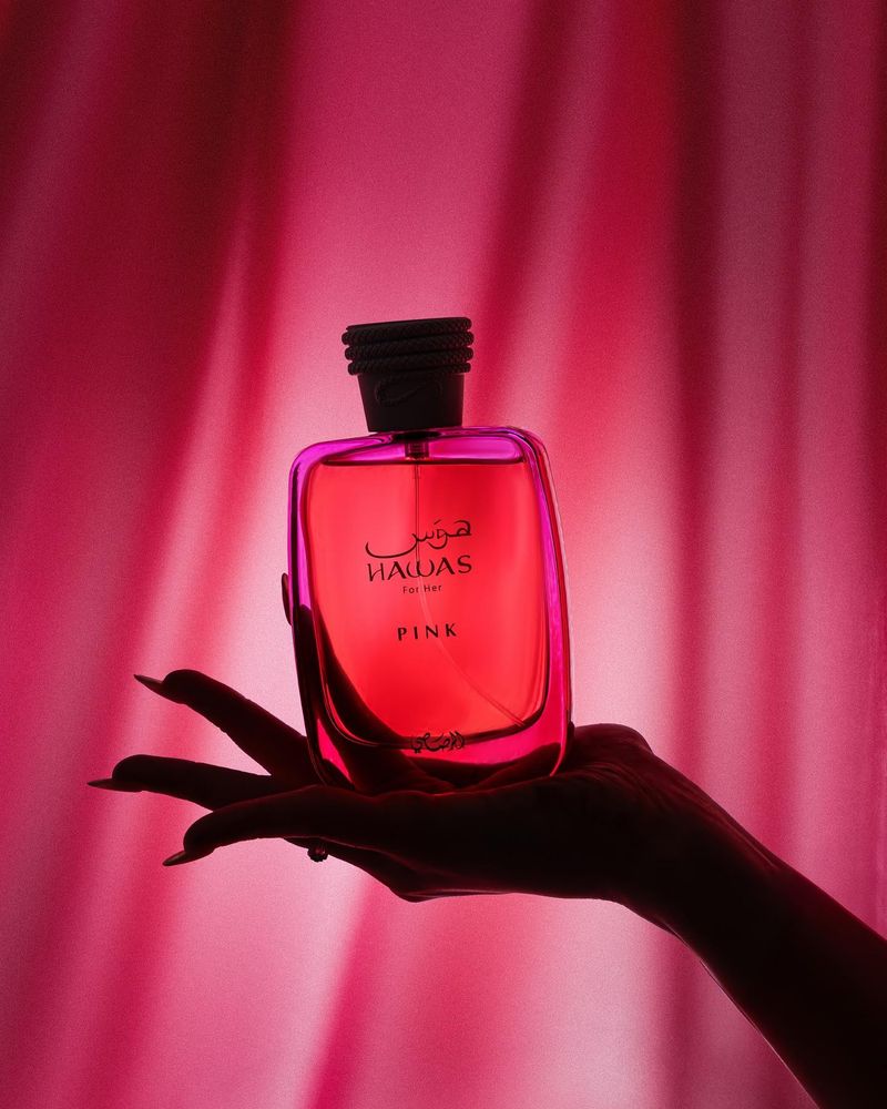 Hand holding a red Rasasi perfume bottle